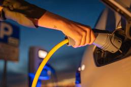 Woman plugging a charging cable into her electric car